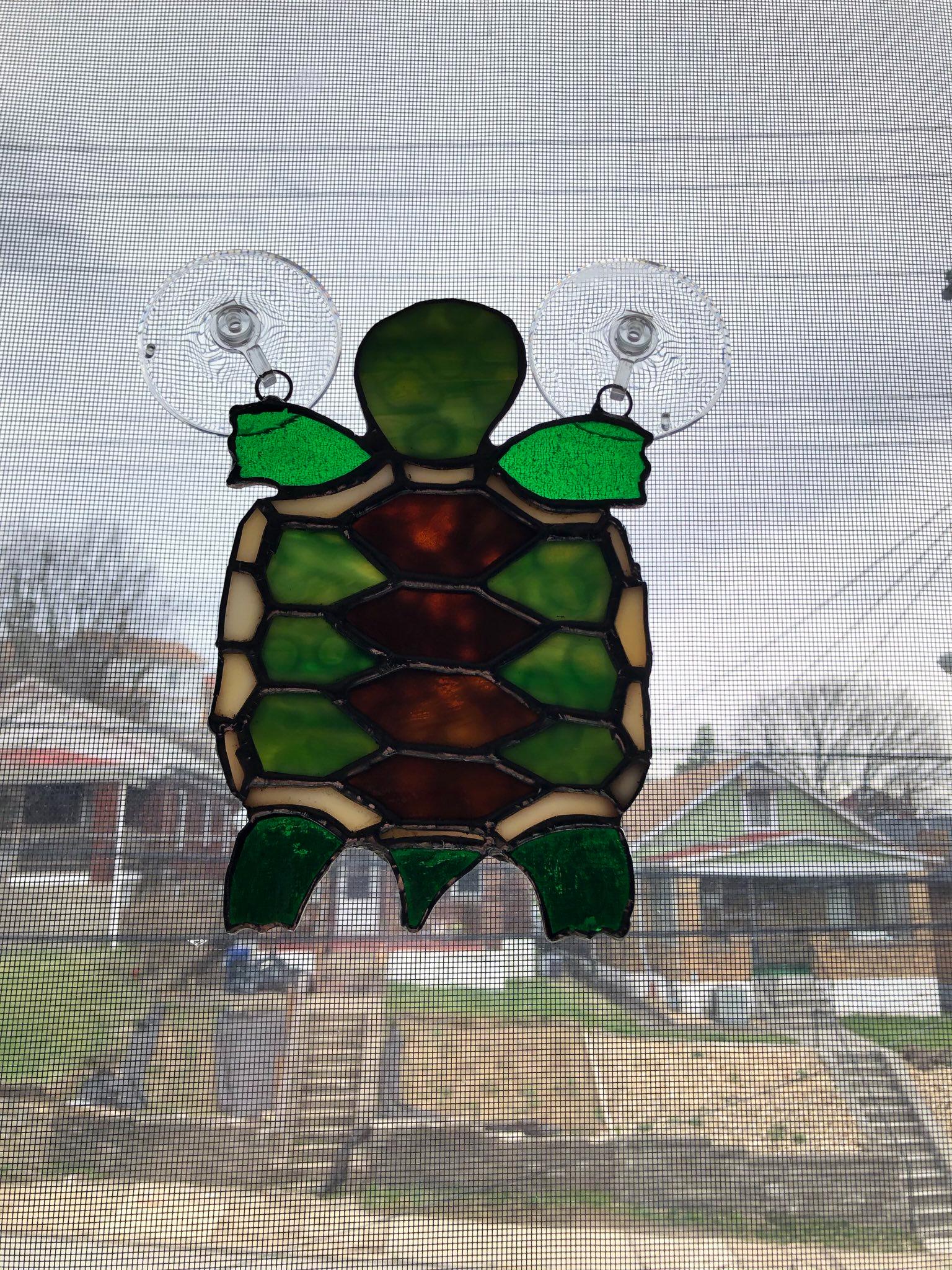 A stained glass turtle that is hung on a window.